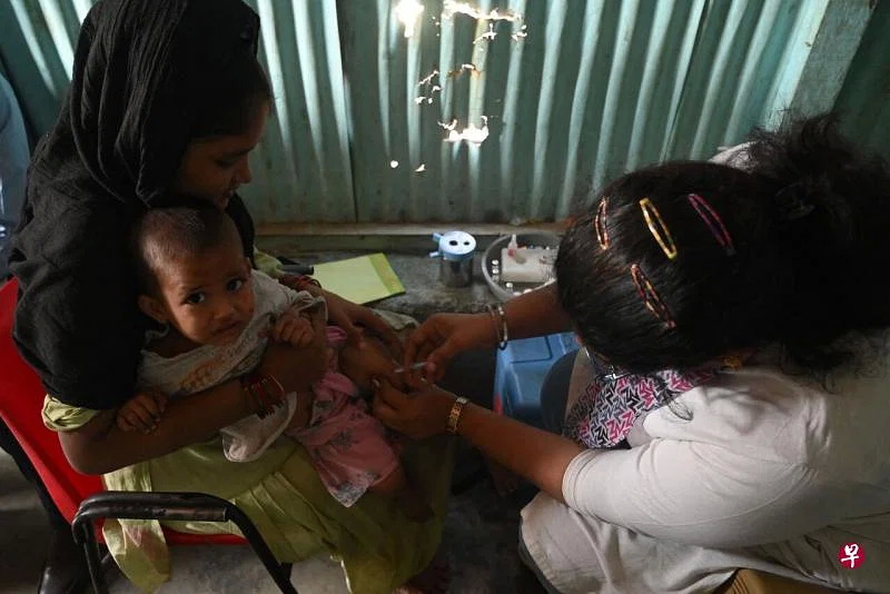 一名工作人员星期三（11月23日）在暴发麻疹疫情的印度金融中心孟买，为一名孩童注射疫苗 ... ...